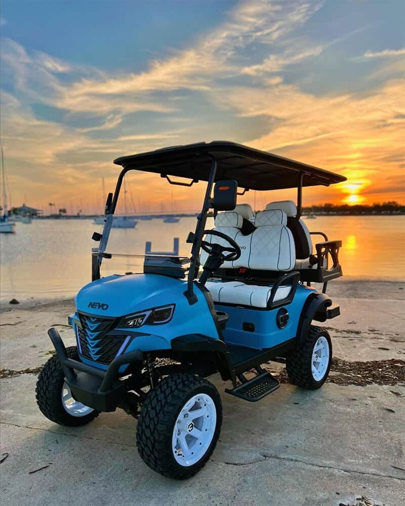 Blue NEVO 4-seater golf cart at sunset